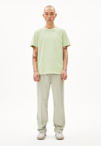 Hellgrünes Baumwoll-T-Shirt, kombiniert mit hellgrünen, lockeren Hosen. Das Outfit zeichnet sich durch ein einfaches Design ohne sichtbare Muster oder Akzente aus.