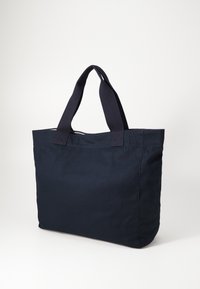 Ναυτικό μπλε καμβάς τσάντα tote με διπλές υφασμάτινες λαβές. Ορθογώνιο σχήμα, λεία υφή και χωρίς ορατά αξεσουάρ ή μοτίβα.