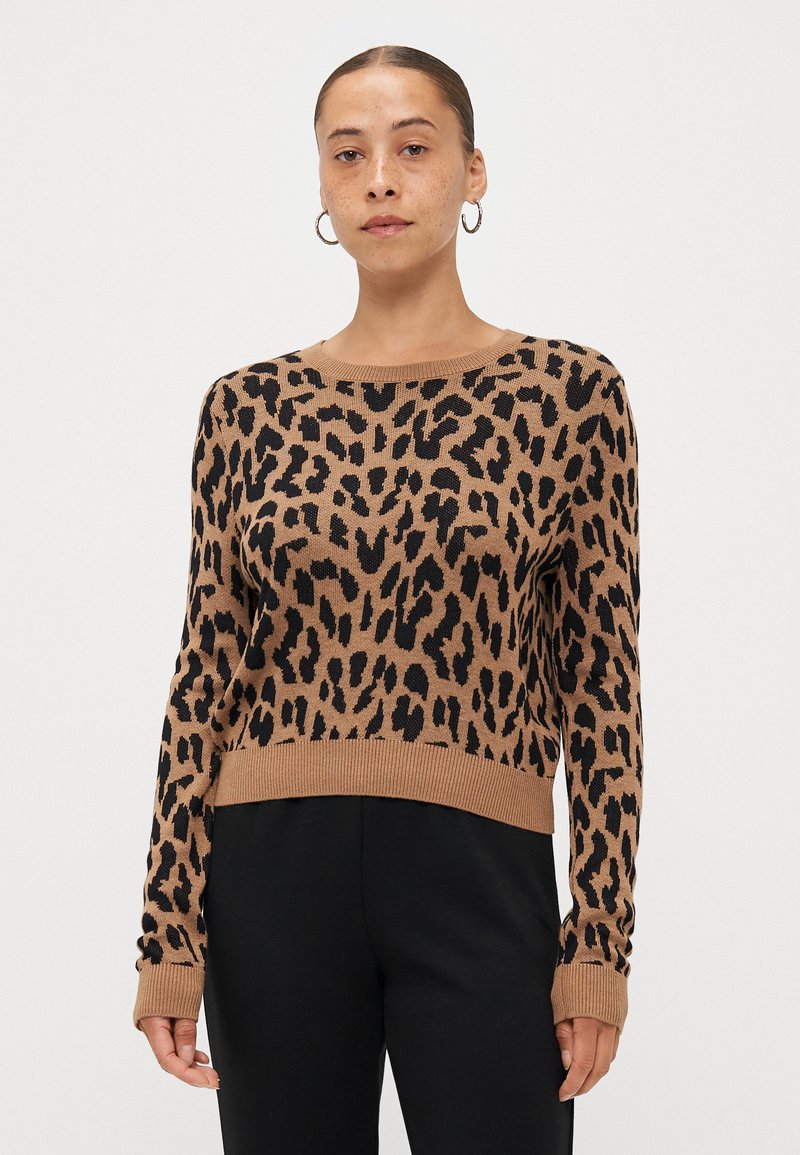 Luipaardprint trui in bruin en zwart, gebreide stof, ronde halslijn, geribde manchetten en zoom, cropped stijl. Zwarte broek eronder.