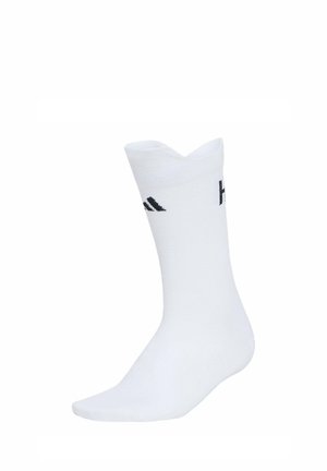 Bílá ponožka po lýtka s černým logem Adidas na boku, zobrazená vzpřímeně na bílém pozadí.