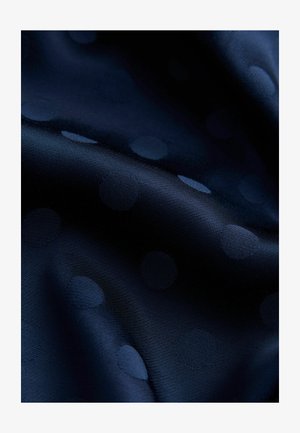 Material albastru marin cu buline subtile în relief. Textură netedă, cu un luciu ușor, care evidențiază modelul de buline pe un fundal închis.