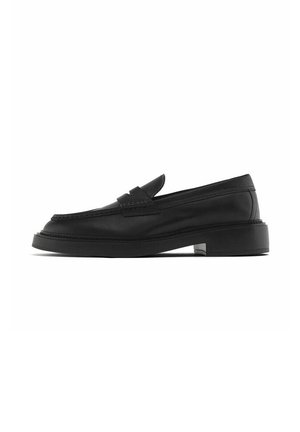 Mocassino penny in pelle nera con tacco rialzato, punta moc cucita e dettaglio classico con cinturino, mostrato di profilo su sfondo bianco.