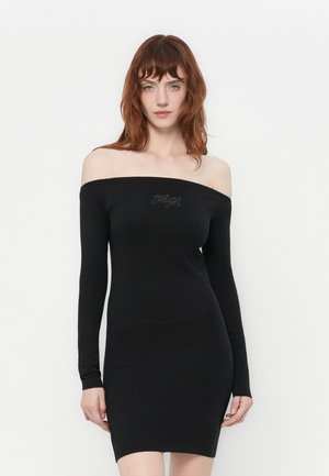 Svart avskåret kjole med lange ermer, tettsittende fasong og en jevn tekstur. Har rhinestonesdetaljer ved halsen.