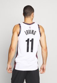 Maillot de basket blanc avec des accents multicolores, portant le nom "IRVING" et le numéro "11" en noir gras. Texture de tissu lisse.