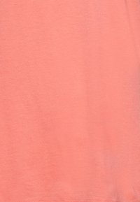 Korala t-shirt wykonana z miękkiej bawełny, o gładkiej fakturze, bez widocznych wzorów ani akcentów, prezentująca prosty, jednolity kolor.