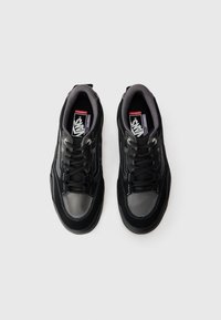 Black sneakers with a textured leather and mesh upper, grey accents, and contrasting white stitching. Features laces and padded collar.
