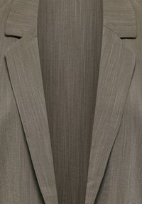 Pilkas švarkas su lygiu, tekstūruotu audiniu. Turi įpjautas atlapus, formuotą kirpimą ir subtilų žuvies kaulo raštą.