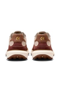 Bruna och beige träningsskor med en överdel i mocka och läder, med en texturerad sula och en guldlogotyp på hälen.