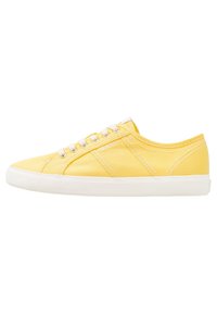 Gul canvas-sneaker med vit gummisula, rund tå och kontrasterande sömmar. Har snörning och logotypdetalj på sidan.