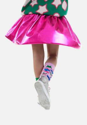 Rosa metallische Rock mit ausgestellter Form, kombiniert mit bunten gemusterten Socken und weißen Sneakers, die lebendige und glänzende Texturen präsentieren.