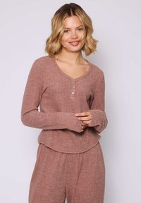 Set da lounge a costine in tono mauve tenue, con scollatura a V, tre bottoni e maniche lunghe con polsini svasati. Tessuto morbido e strutturato.