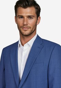 Blazer in Blau mit strukturierter Oberfläche aus gewebtem Stoff, ausgestattet mit Jersey-Revers, einer einzigen Tasche und einem weißen Hemd mit Kragen darunter.