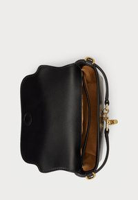 Μαύρη δερμάτινη τσάντα χειρός με απαλή, καμπυλωτή σχεδίαση. Ο εσωτερικός χώρος είναι επενδεδυμένος με καφέ ύφασμα και διαθέτει χρυσές λεπτομέρειες για το κλείσιμο και την προσαρμογή της θηλιάς.