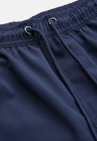 Marinblå idrottshorts med elastisk midja och dragsko, slät yta och synliga sömmar.