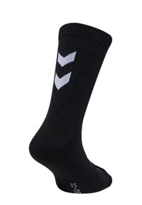 Chaussettes noires en tissu doux et texturé, avec des motifs de flèches blanches sur le côté extérieur et un talon renforcé.