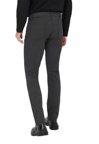 Pantalon gris foncé coupe slim, avec poches arrière et texture lisse. Porté avec des chaussures noires, présentant une coupe droite.