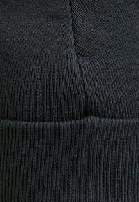 Czarna dziana czapka z miękkiej włóczki. Posiada prążkowaną fakturę oraz złożony mankiet, co zapewnia ciepło i dopasowanie.