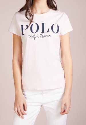 Woman wearing a white short-sleeve T-shirt with "POLO Ralph Lauren" printed in large navy letters on the front.