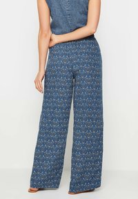 Kalhoty s širokými nohavicemi v modré látce s paisley vzorem a elastickým pasem. Hladký materiál s uvolněným střihem, vhodné pro každodenní nošení.