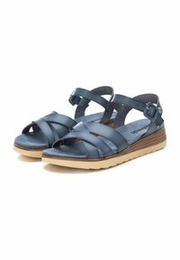 Sandalias de cuero azul marino con correas cruzadas, hebilla ajustable y plantilla acolchada. Suela de goma marrón claro con patrón texturizado.