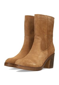 Botas de tobillo de ante marrón con punta redondeada, detalles de costura y un tacón de bloque texturizado. Presenta un material suave y liso, sin elementos de metal visibles.