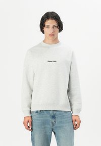 Grijze katoenen sweatshirt met ronde hals en ribgebreide boorden en zoom; met het 'Original Studio' logo in het zwart op de borst; gecombineerd met lichtblauwe jeans.