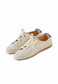 Zapatillas de cuero beige con una puntera de ante, cordones planos y un acento en el talón azul. Presentan una textura suave y una forma redondeada.