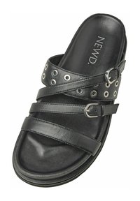 Svart slide-sandal med korsade remmar i läder. Utrustad med silverfärgade öglor, justerbar spänne och en strukturerad fotbädd för komfort.