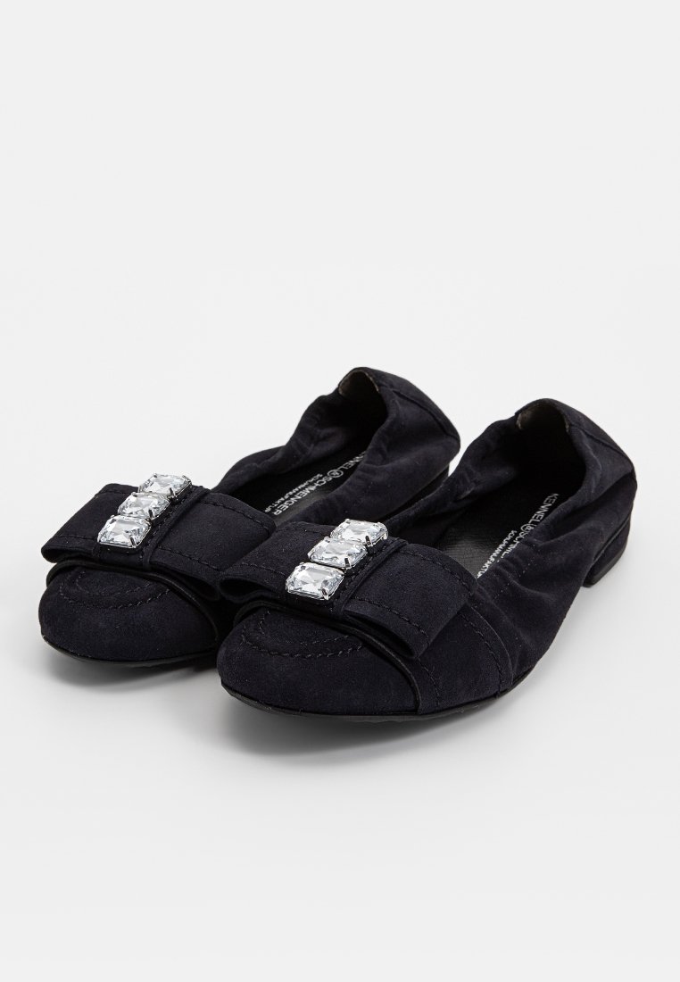 Schwarze Wildlederschlupfschuhe mit runder Zehenform, die eine dekorative Schleife und drei klare Kristallakzente an der Vorderseite aufweisen. Glatte Textur, einfaches Anziehen.