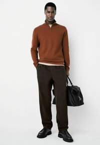 Brown zip-up sweater, beige undershirt, brown trousers, black shoes, holding a black leather bag. Smooth texture, classic fit, neutral tones.