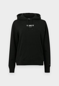 Čierna mikina s kapucňou z mäkkej látky, s vreckom na brušku a kapucňou so sťahovacou šnúrkou. Na prednej strane je biele logo s nápisom "TOMMY JEANS".