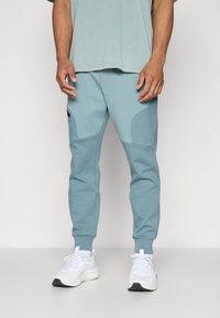 Under Armour UNSTOPPABLE FLEECE - Tracksuit bottoms - jasper blue/serpentine/black