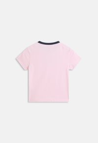 Ροζ ανοιχτόχρωμο κοντομάνικο μπλουζάκι με στρογγυλή μαύρη λαιμόκοψη, εμφανιζόμενο από πίσω σε απλό ανοιχτό γκρι φόντο.