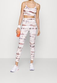 Urheiluliivit ja legginssit pehmeästä, joustavasta kankaasta, jossa on akvarellikuvaus vaaleanpunaisista, ruskeista ja valkoisista sävyistä.