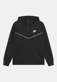 Černá mikina se zipem a texturovaným povrchem, s bílým logem Nike na levé části hrudi a reflexním pruhovaným designem přes hrudník.