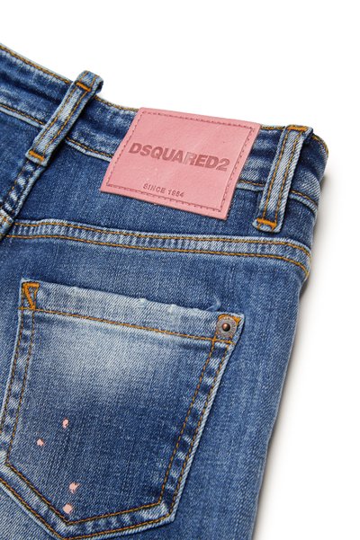 Blå denimjeans med et rosa skinnlapp som har "DSQUARED2" og "SINCE 1964". Slitte detaljer på baklommen, gullfargede sting.