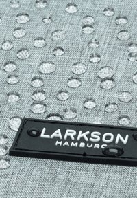 Tissu texturé gris avec des gouttes d'eau claires et une étiquette rectangulaire noire portant "LARKSON HAMBURG" en lettres blanches.