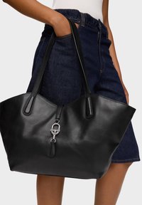 Borsa tote in pelle nera con texture liscia, caratterizzata da manici lunghi e un dettaglio in metallo argentato nella parte frontale. Design ampio e aperto.