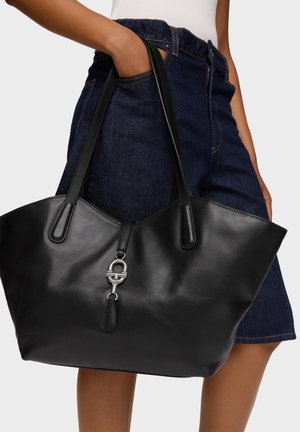 Bolso tote de cuero negro con textura lisa, que presenta asas largas y un detalle de herrajes plateados en la parte frontal. Diseño amplio y abierto.