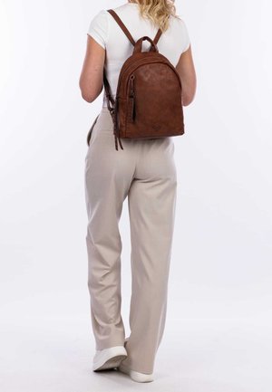 Brązowy skórzany plecak o zaokrąglonym kształcie, z regulowanymi paskami i górnym uchwytem. Posiada zasuwaną kieszeń z boku oraz teksturowane wykończenie.