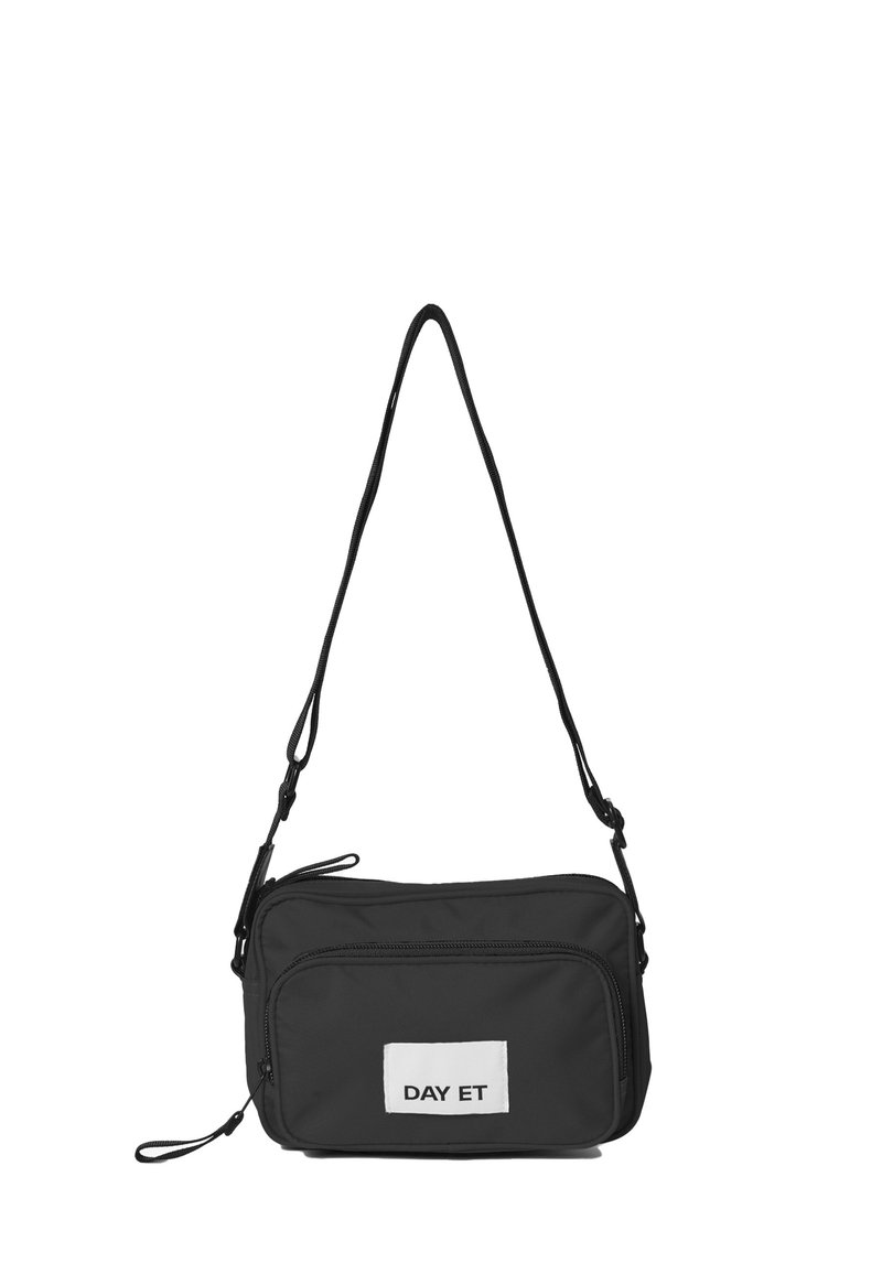 Sort nylon crossbody taske med rektangulær form, justerbar rem, to lynlåslommer og et hvidt skilt med "DAY ET" tekst.