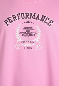 Roza bombažna majica s temnim grafičnim potiskom. Napis: "PERFORMANCE" in "PUSH YOUR LIMITS" s dekorativnimi lovorjevimi detajli.