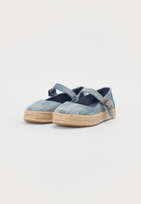 Sapatos de espadrille em denim com um topo azul texturizado, uma fita que atravessa o pé e uma sola trançada de juta. Design rústico com acentos contrastantes.