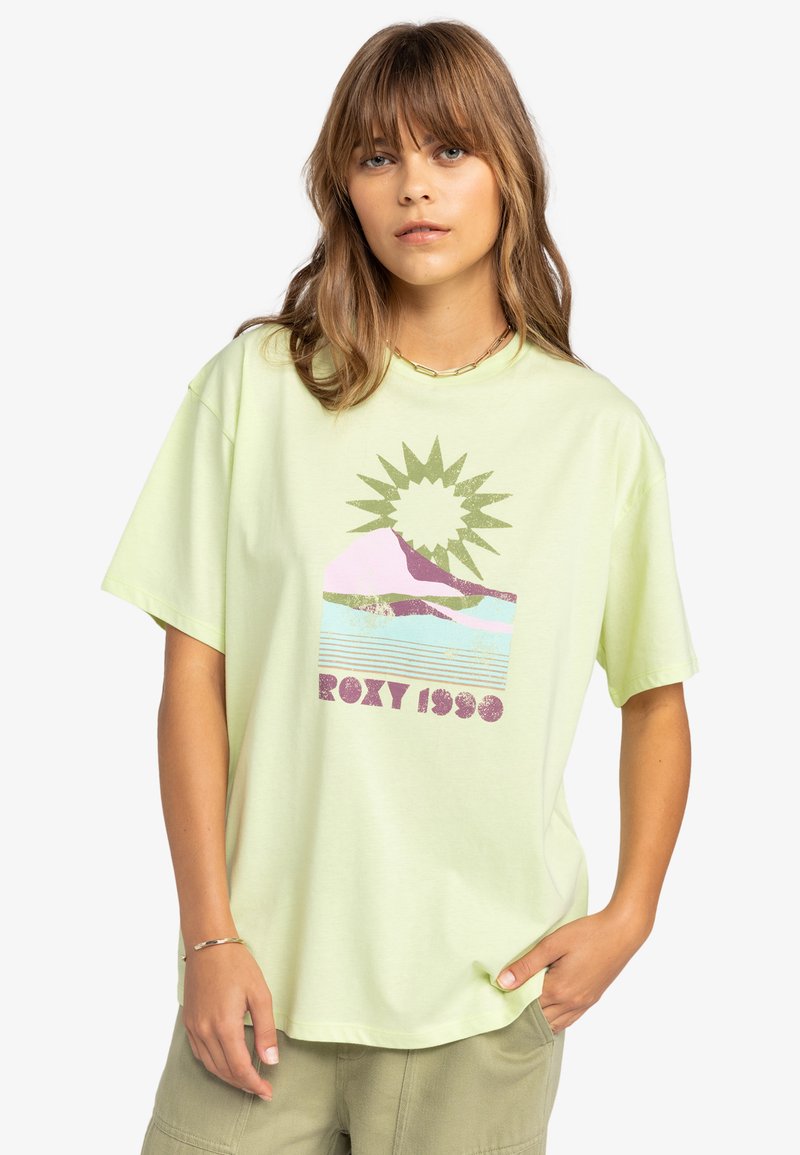 Vihreä t-paita, joka on valmistettu puuvillasta, ja siinä on graafinen printti, jossa on aurinko, vuoret sekä teksti "ROXY 1989" violetilla ja vaaleanpunaisella. Rentomallinen.