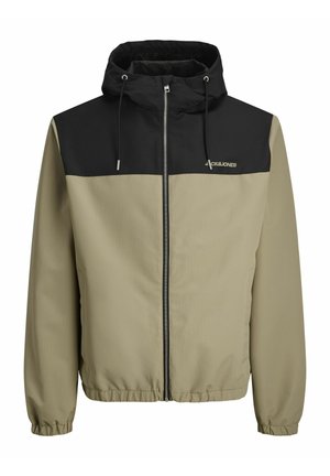 Jachetă cu glugă, cu o secțiune superioară neagră și o secțiune inferioară maro deschis. Dispune de un fermoar frontal, manșoane elastice și șnururi ajustabile.