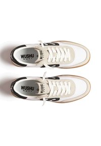 Un paio di sneaker Wushu Ruyi bianche e beige con accenti e lacci neri, viste dall'alto su uno sfondo bianco.