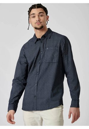 Marineblå skjorte med knapper, der har et geometrisk mønster i hvid. Lange ærmer, let stof og en diskret brystlogo-detalje.