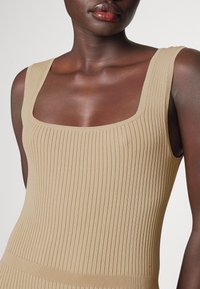 Beige Ripptop mit quadratischem Ausschnitt und breiten Trägern, mit einem strukturierten Stoffmuster und figurnahem Schnitt.