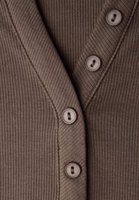 Brauner, gerippter Cardigan mit V-Ausschnitt und fünf Knöpfen. Die Knöpfe sind hellfarben mit dunkler Naht. Saubere Nähte umrahmen die Kanten.