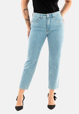 Jeans in denim blu chiaro con ricami floreali argentati, vita alta e design a gamba affusolata. Abbinati a scarpe nere con tacco alto.